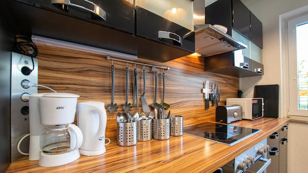 Eine moderne Küche mit einer Holz Arbeitsplatte, Edelstahlgeräten und Küchenutensilien an der Wand.