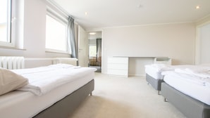 Ein modernes Hotelzimmer mit zwei Betten, einem Schreibtisch und Blick auf die Stadt.