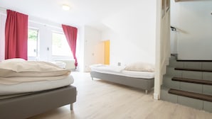 Ein Schlafzimmer mit zwei Betten, einer Treppe und Blick ins Freie.
