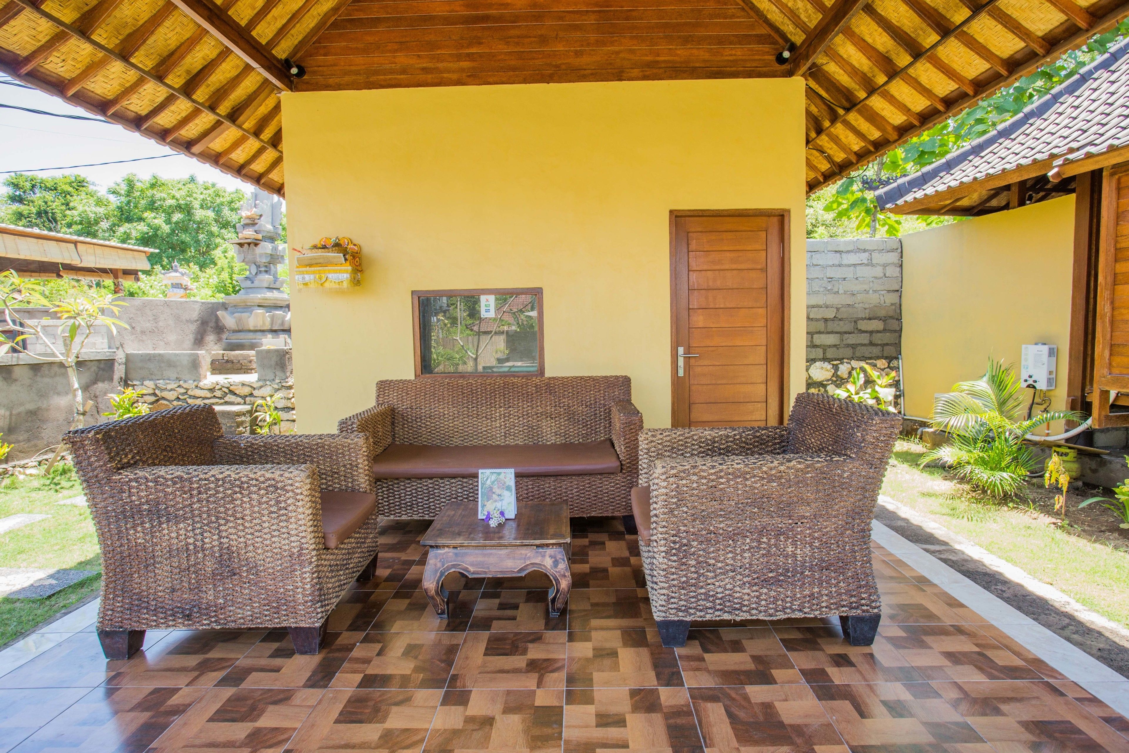 A covered outdoor seating area with wicker furniture and a tiled floor.