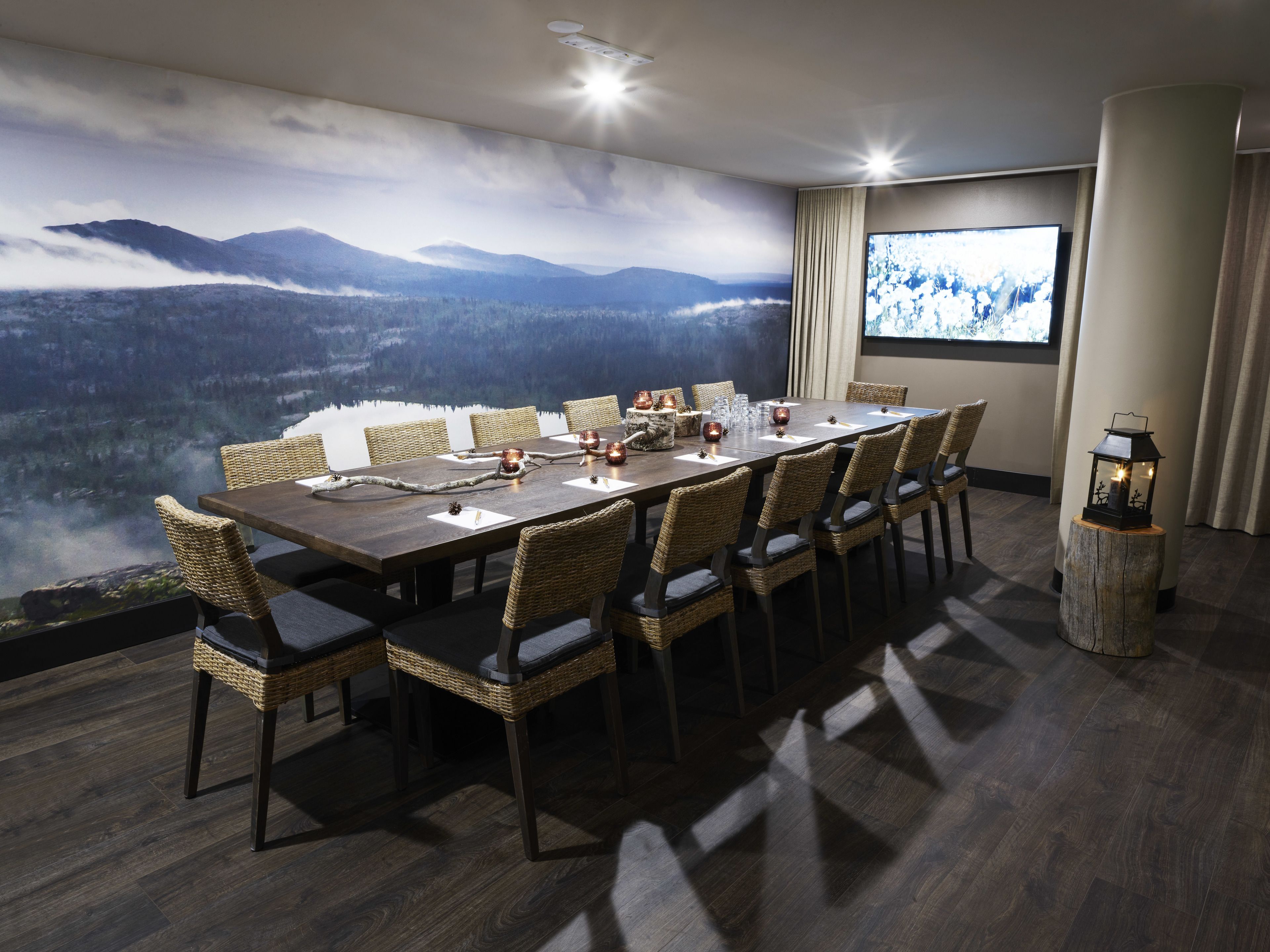 A conference room with a panoramic mountain view, a large table with chairs, and a projector screen.