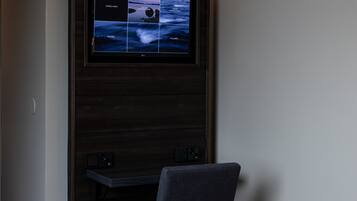 Ein Hotelzimmer mit Bett, Schreibtisch und Wandfernseher.
