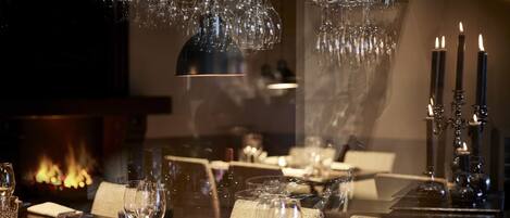 A dimly lit dining area with a table set for two, featuring crystal glasses and a candelabra.