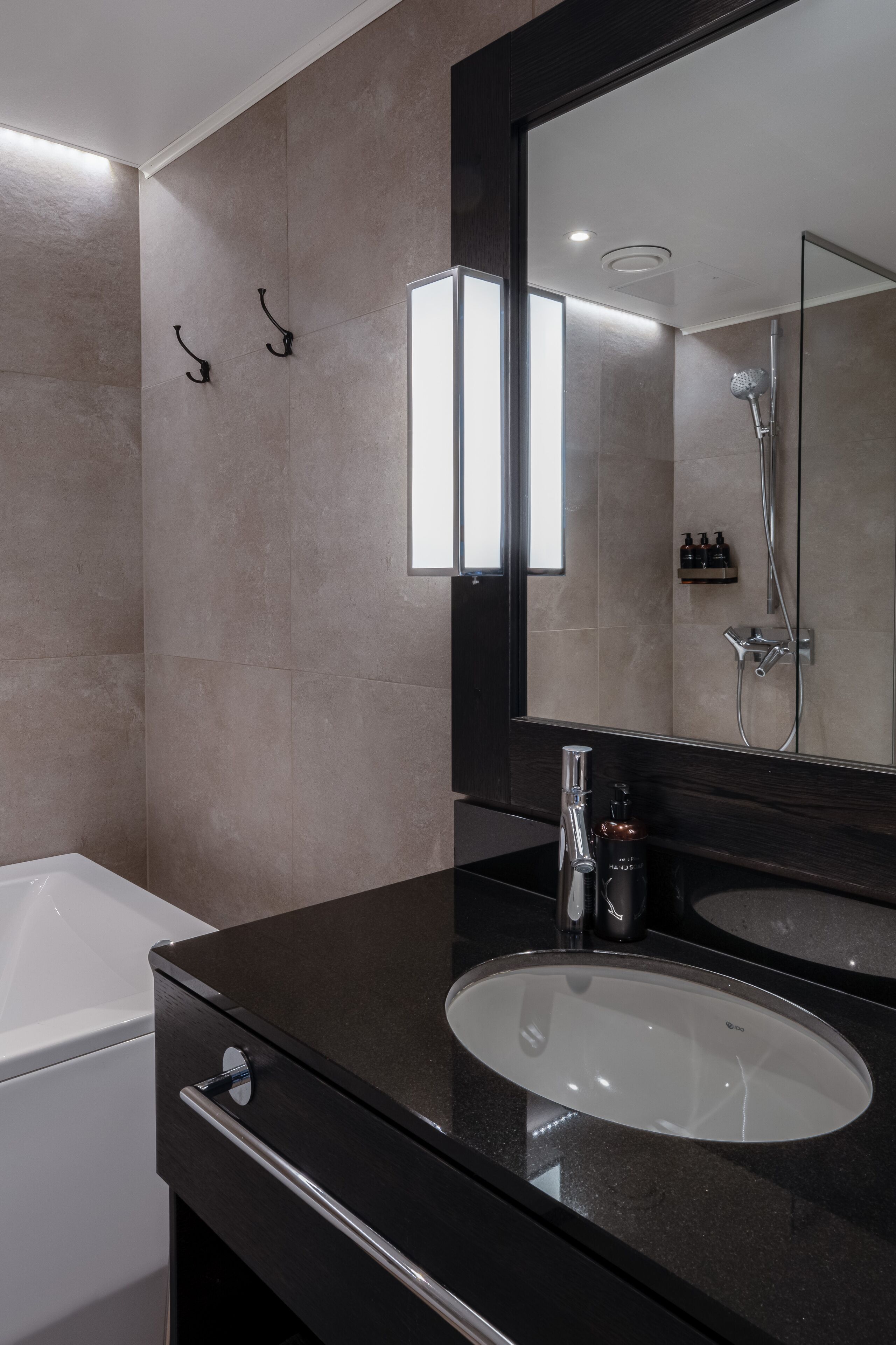 A modern bathroom with a large mirror, a bathtub, and a sink.