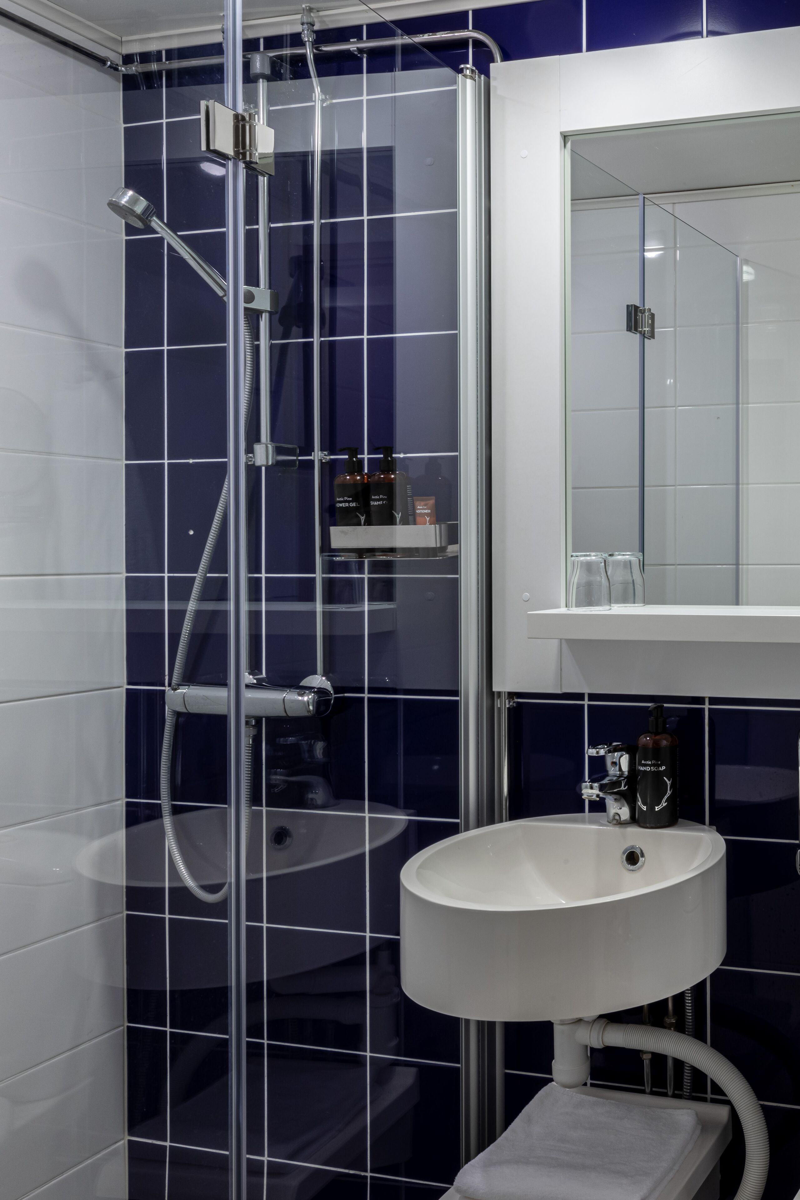 Un baño con ducha envuelta en vidrio, un lavamanos blanco y un espejo encima.
