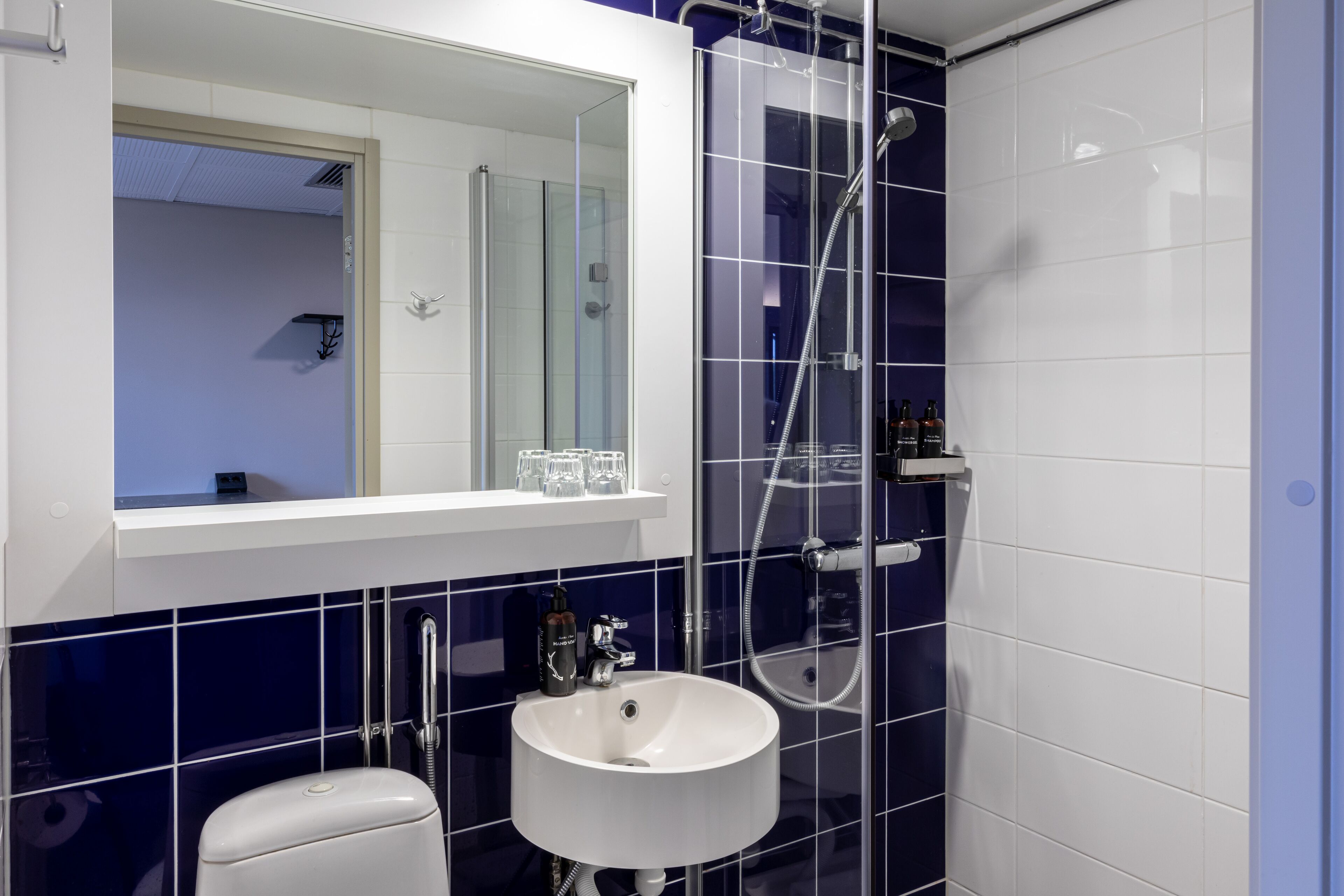 A modern bathroom with a white sink, a glass-enclosed shower, and a mirror above the sink.