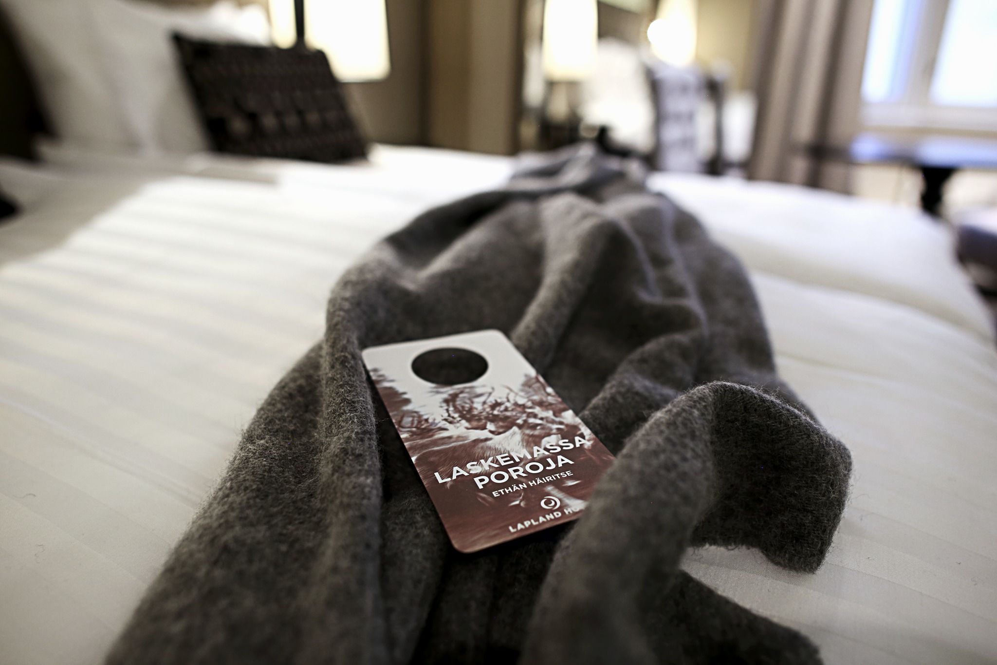 Une chambre d’hôtel avec un lit bien fait, une étiquette sur la couverture du lit et une fenêtre en arrière-plan.