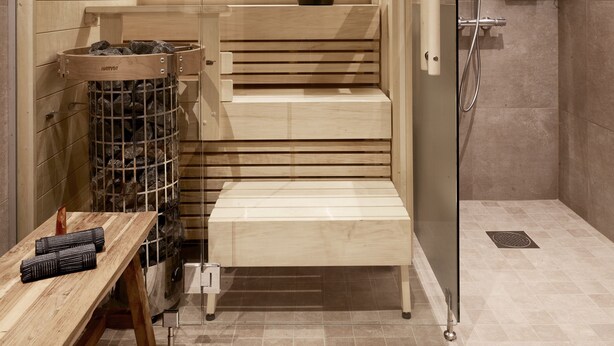 A sauna with wooden benches, a glass door, and a shower area. - Lapland Hotels Kuopio (Kuopio)