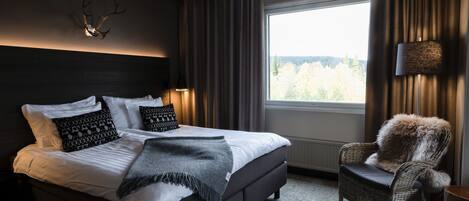 Un dormitorio moderno con una cama grande, cabecero oscuro y decoración de cornamenta de ciervo.