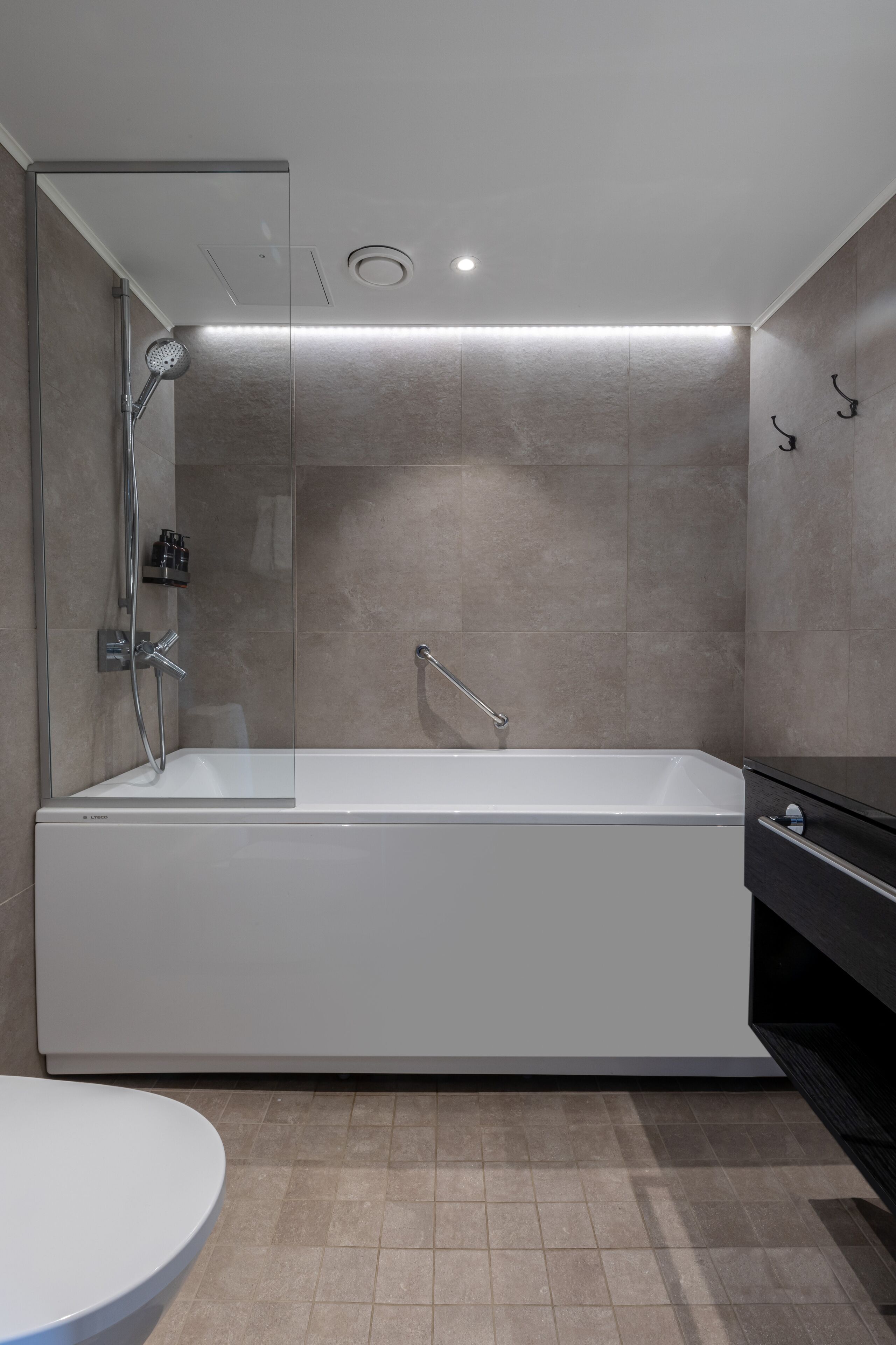 A modern bathroom with a large bathtub, a glass-enclosed shower, and a separate sink area.