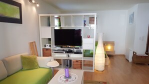 Ein Wohnzimmer mit einem grünen Sofa, einem weißen Couchtisch und einem Fernseher auf einer weißen Unterhaltungsecke.