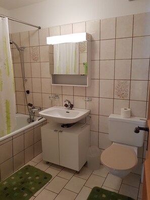 Ein Badezimmer mit Badewanne, Waschbecken, Toilette und einem Spiegel über dem Waschbecken.