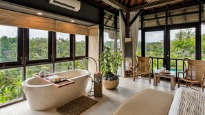 A modern bathroom with a freestanding bathtub, a large window, and a view of lush greenery. - Villa Kelusa Ubud (Payangan)