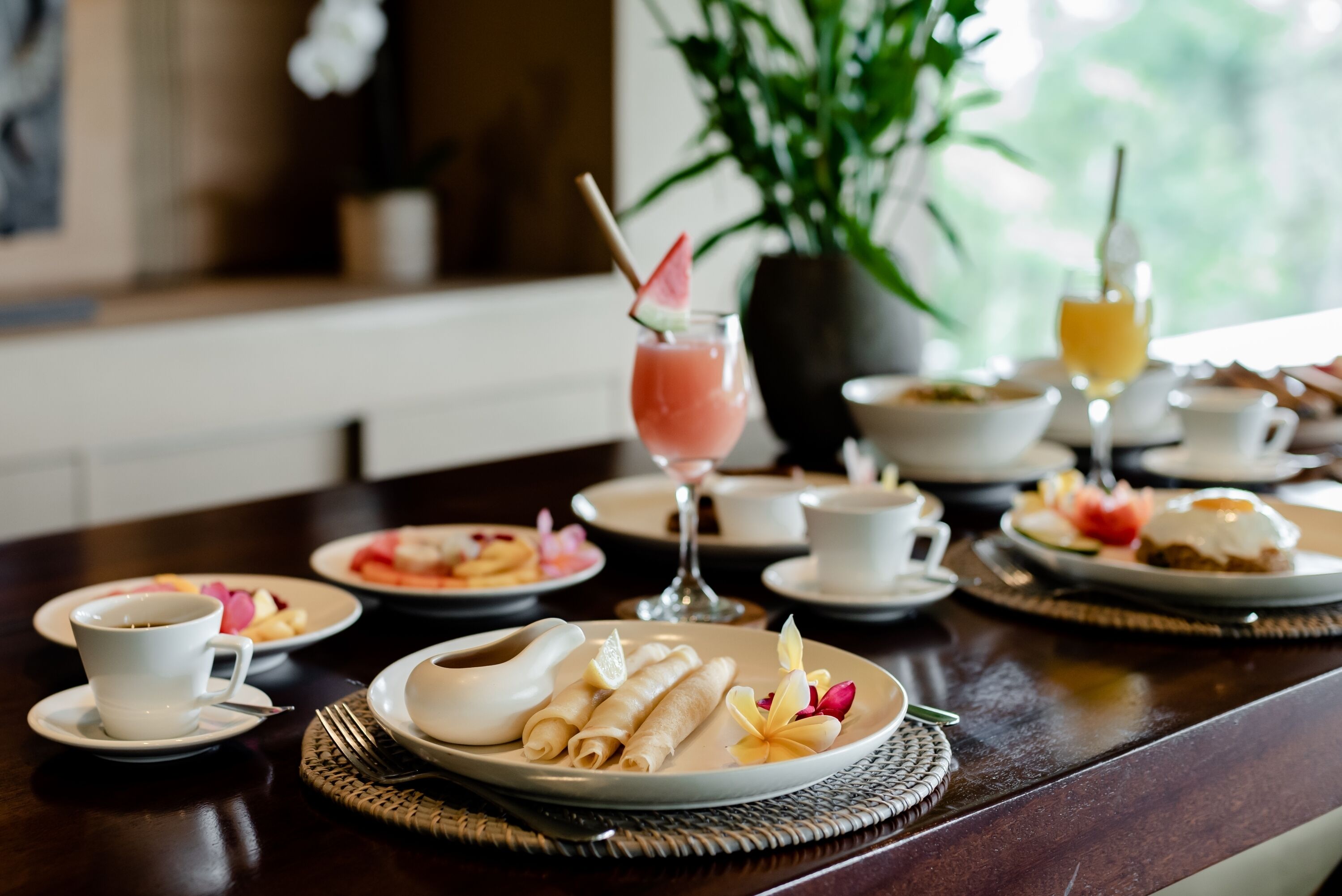 A dining table with various breakfast items including pancakes, a glass of juice, and a cup of coffee.