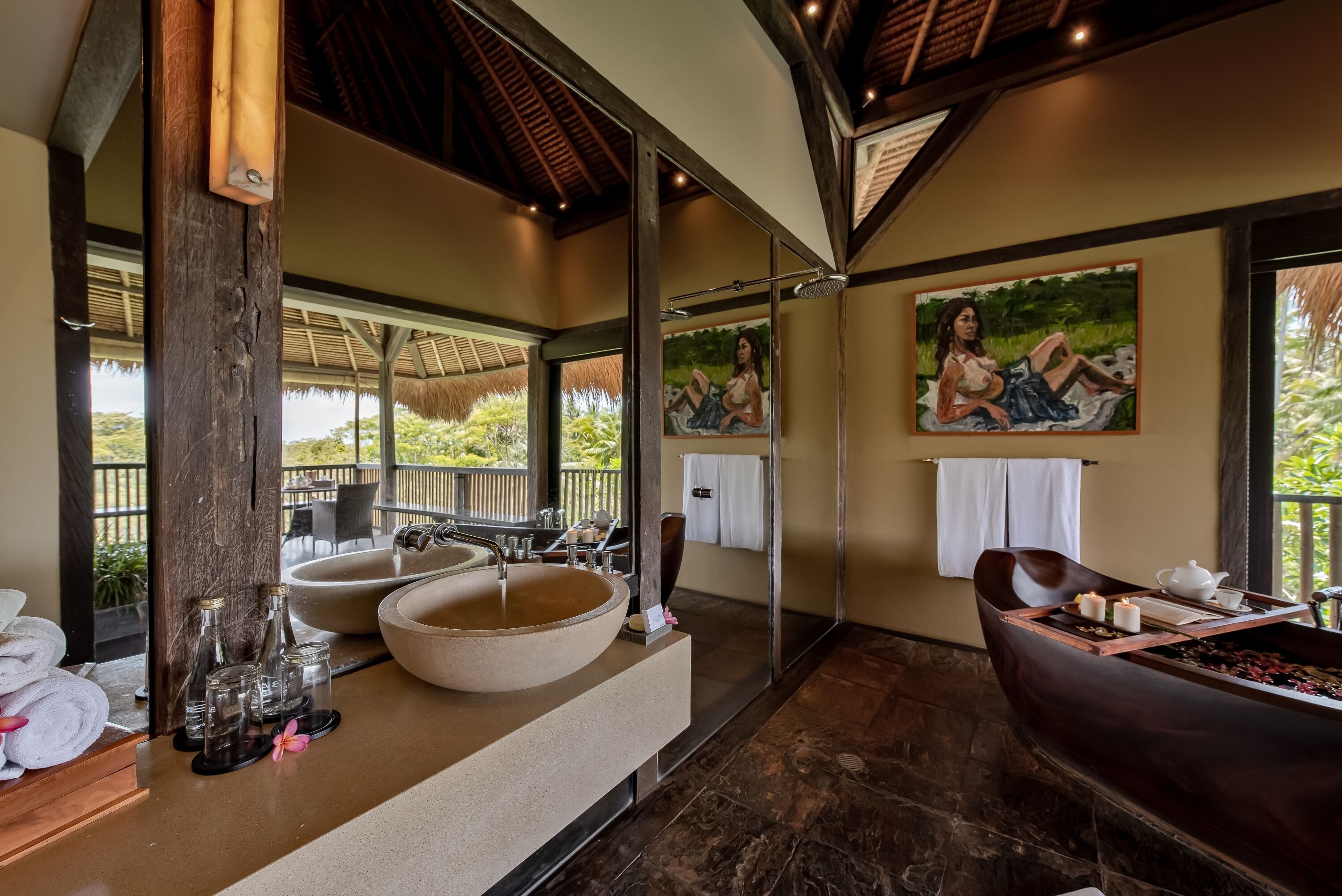 A bathroom with a large mirror, two sinks, a bathtub, and a window with a view of greenery.