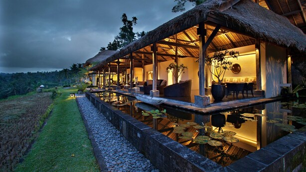 A thatched-roof structure with outdoor seating and a water feature. - Villa Kelusa Ubud (Payangan)