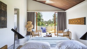 Un dormitorio con una cama, dos sillas, un ventilador de techo y vistas a palmeras.