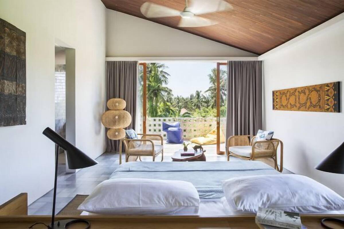 Un dormitorio con cama, dos sillas, un ventilador de techo y vistas al exterior.