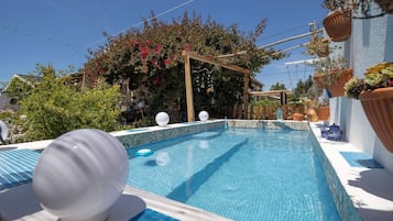 En sÀsongsöppen utomhuspool, parasoller och solstolar
