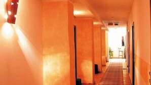 Un pasillo con alfombra estampada, suelo de madera y luminarias fijadas a la pared.