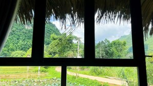 A room with a window overlooking a lush landscape, including a river and a road. - Mai Chau Sky (Mai Chau)
