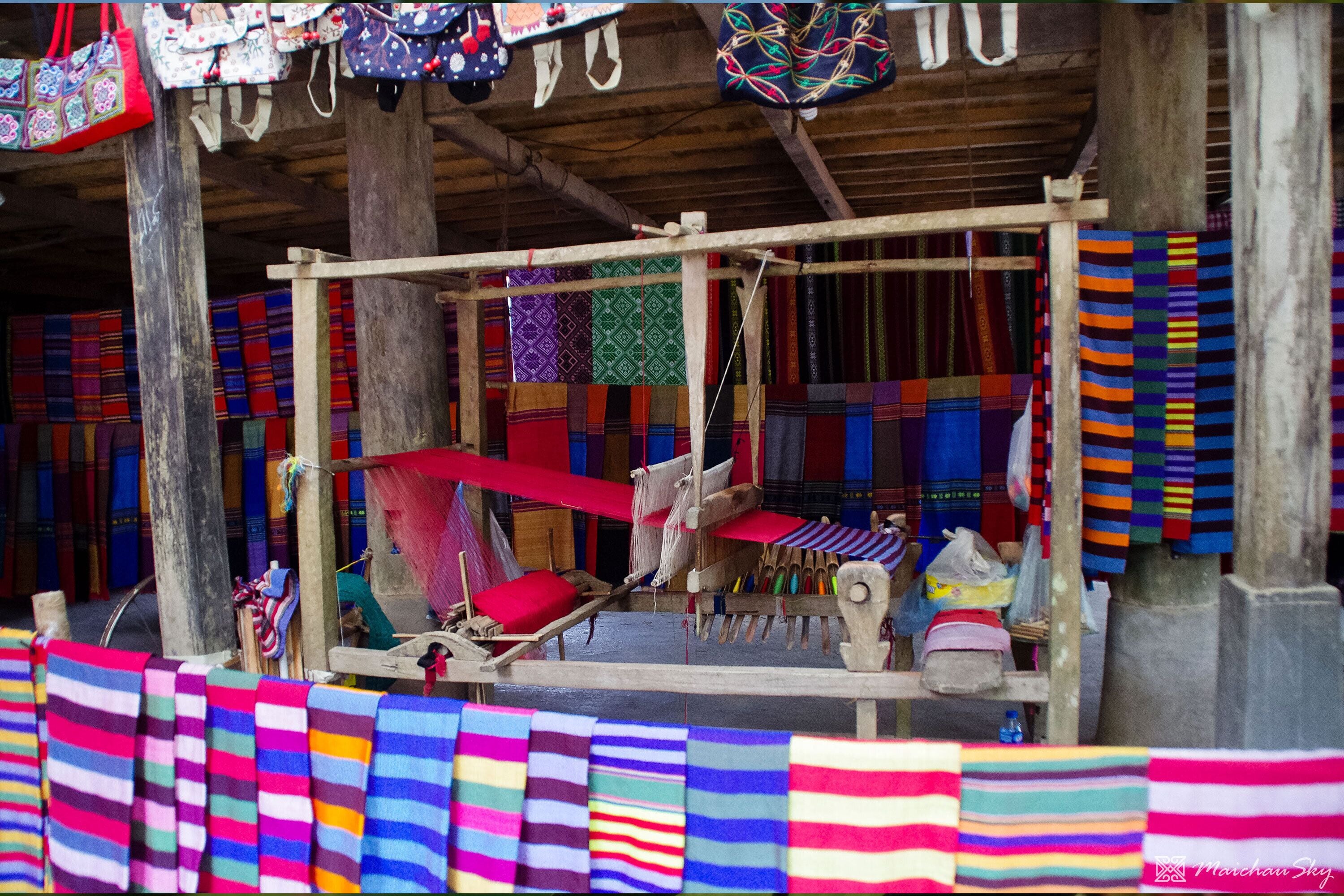 A traditional weaving setup with colorful textiles and a wooden structure.