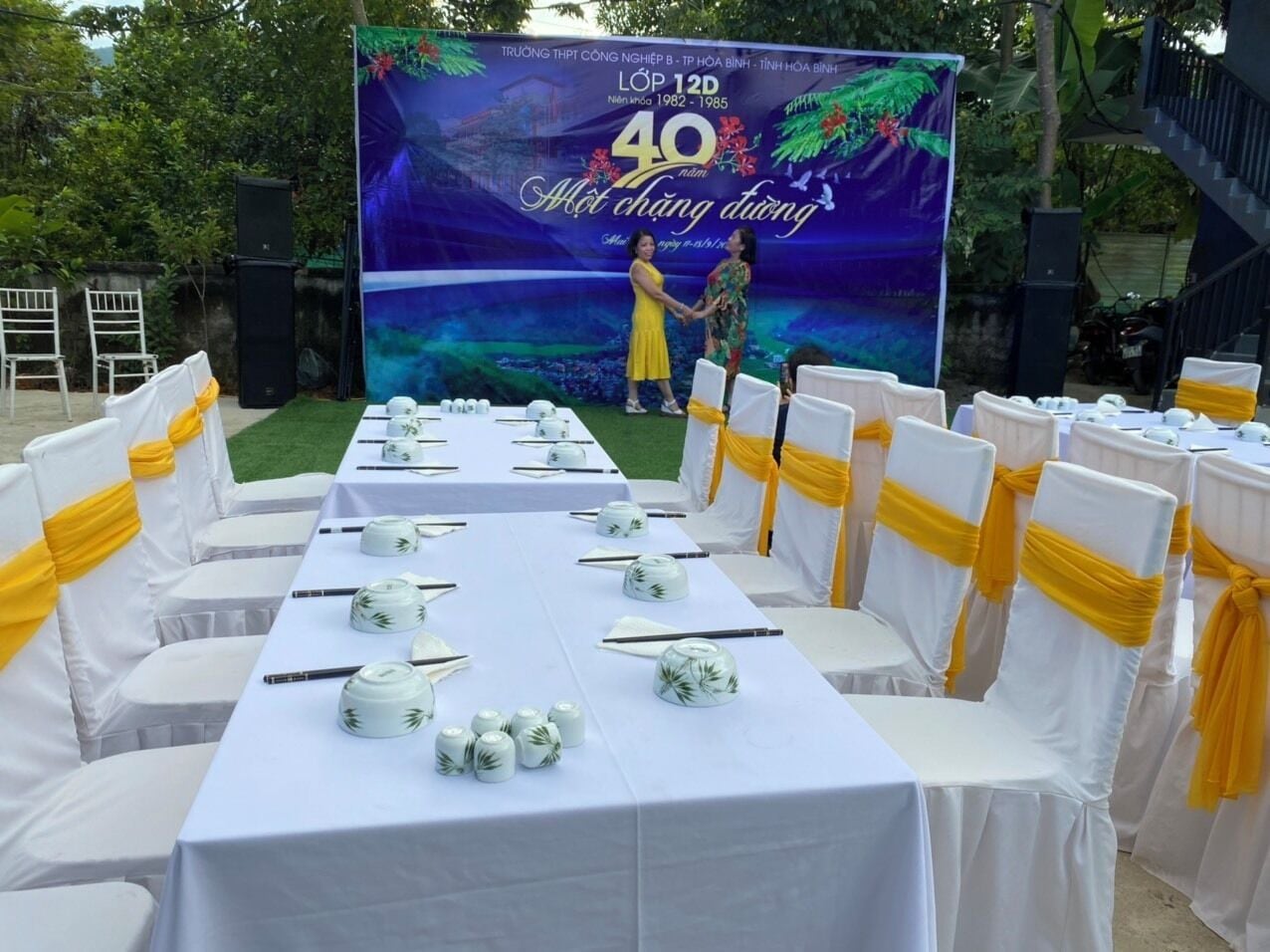 A banquet table set for a formal event with white tablecloths and yellow sashes on chairs.