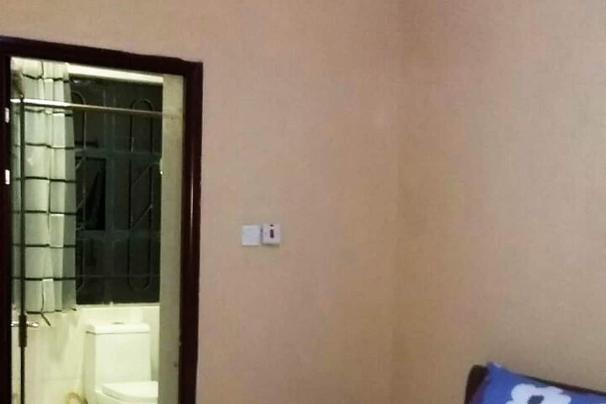 Une chambre avec un lit, une porte donnant sur une salle de bain et un interrupteur sur le mur.