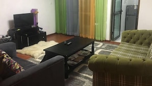 Ein Wohnzimmer mit einer Couch, einem Couchtisch, einem Fernseher und einer kleinen Kommode.