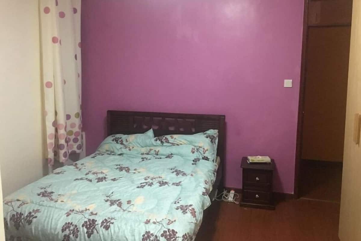 Une chambre à coucher avec un lit, une table de chevet et une porte.