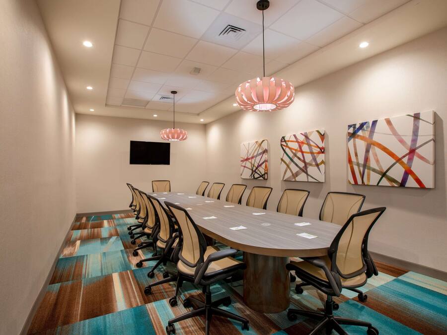A conference room with a long table, chairs, and abstract art on the walls.