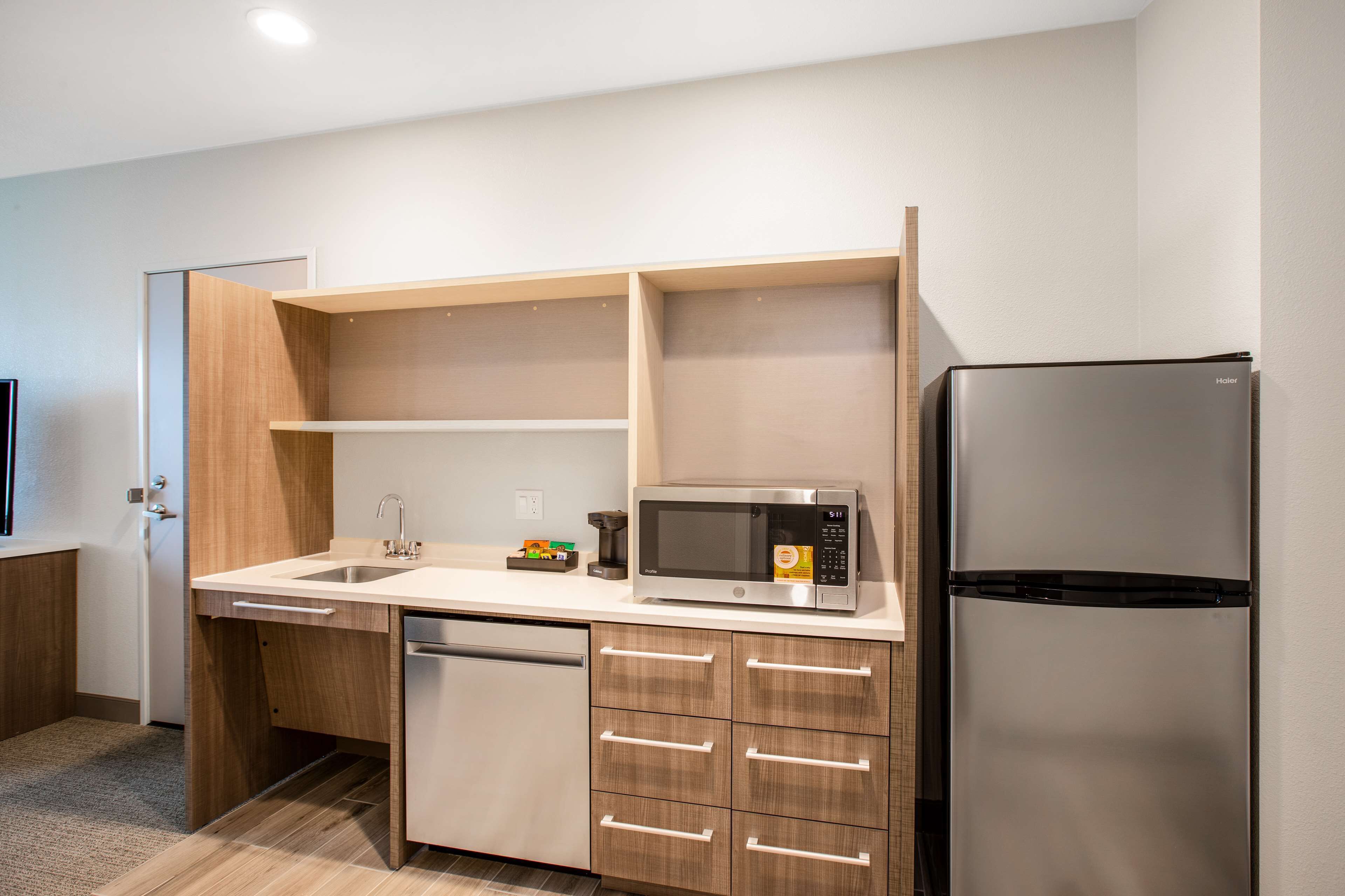 A modern kitchen with a built-in dishwasher, a stainless steel refrigerator, and a microwave on the countertop.