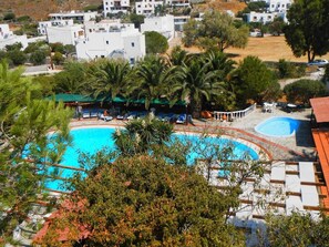 Una piscina rodeada de palmeras y edificios blancos.
