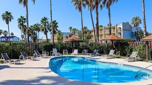Un área de piscina con sillones, palmeras y un edificio que dice "Parklane".