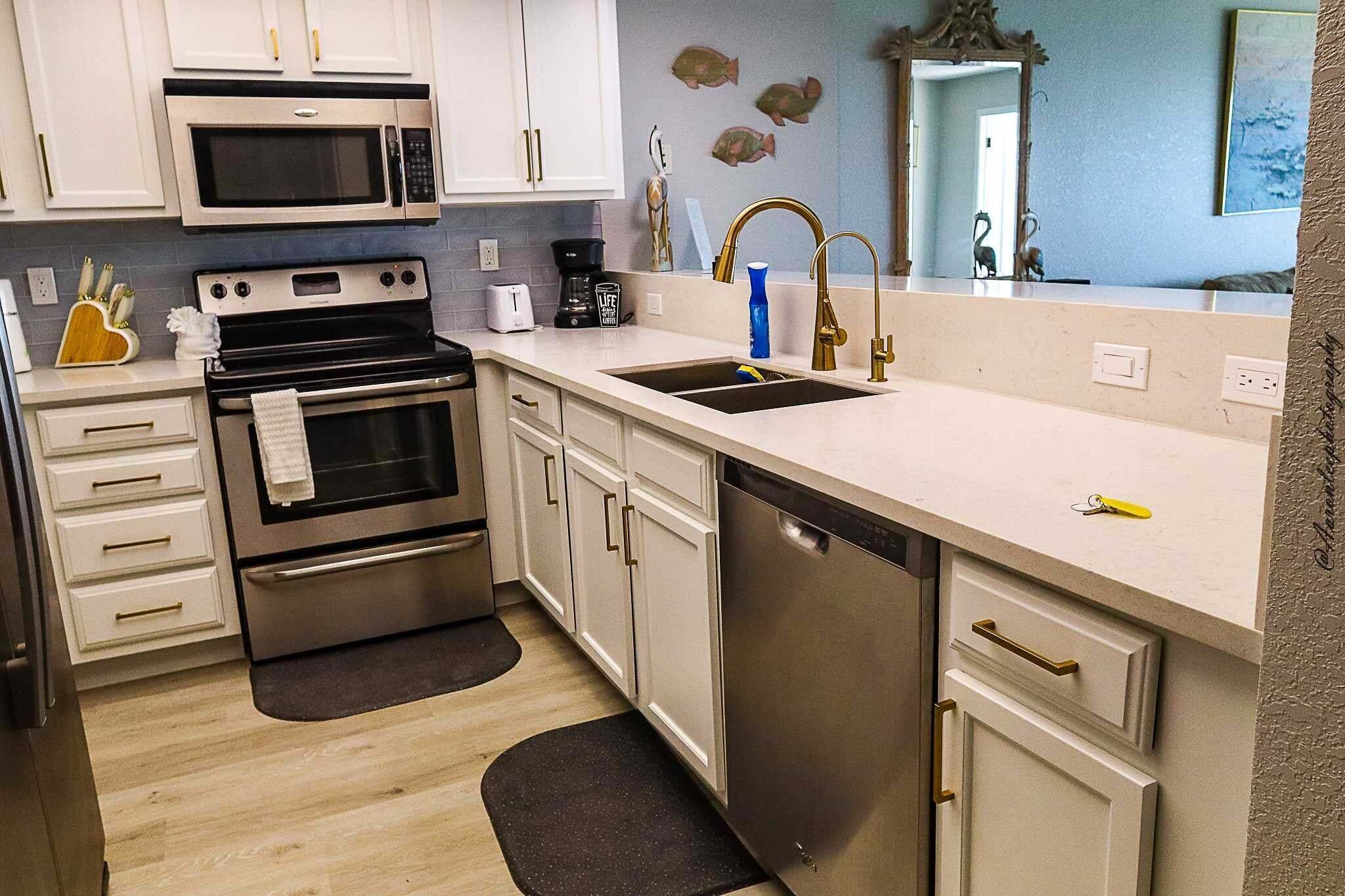 A modern kitchen with stainless steel appliances, a double sink, and white cabinetry.