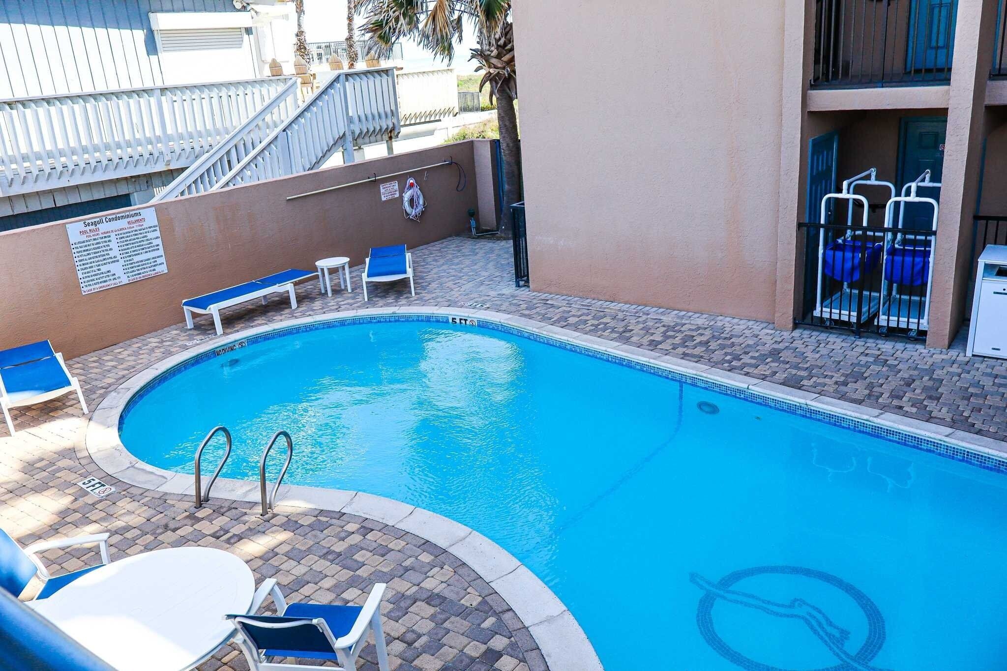 Une piscine avec des chaises longues et un panneau d’affichage.