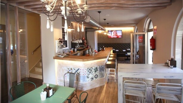 Un restaurant doté d’un bar, d’un plafond en bois et d’un écran de télévision en arrière-plan.