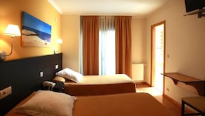 Une chambre d’hôtel avec deux lits, un tableau au mur, un bureau et une télévision.