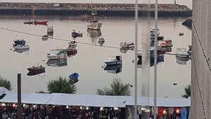 Une vue d’un port avec des bateaux amarrés et une zone de marché avec des tentes et des véhicules.