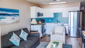 A modern kitchen with white cabinets, a blue backsplash, and stainless steel appliances. - Florence I 307 Minium 1 Bedroom Condo by RedAwning (South Padre Island)