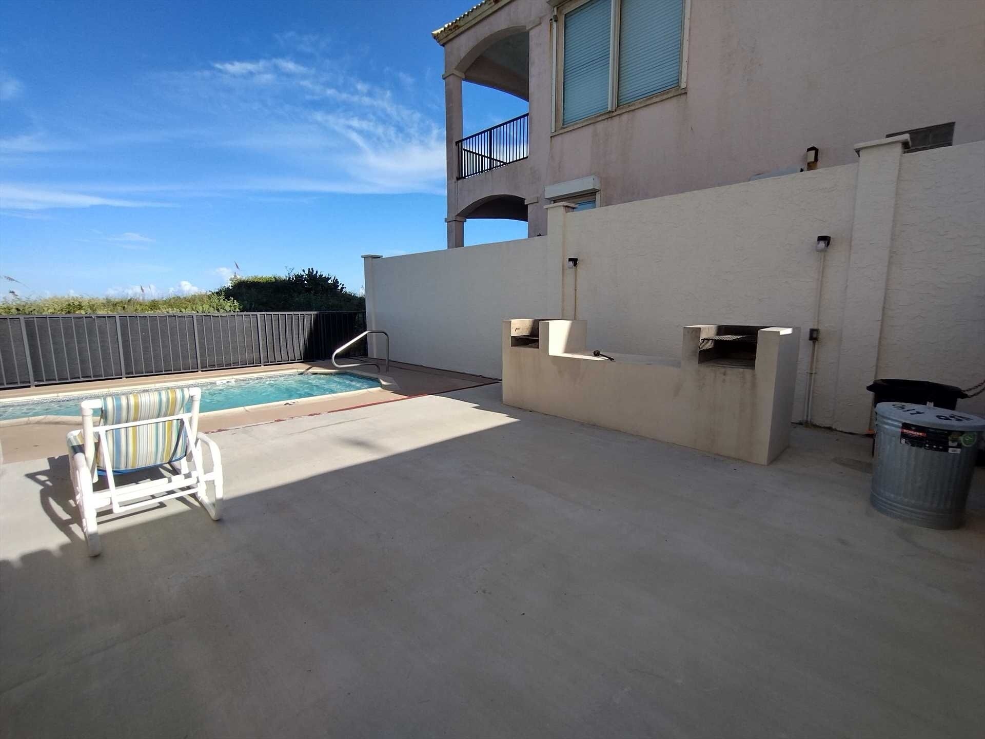A swimming pool with a sun lounger, a concrete deck, and a trash can.