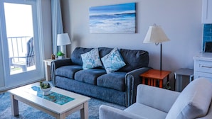 A modern living room with a sofa, a coffee table, and a TV stand. - Florence I 307 Minium 1 Bedroom Condo by RedAwning (South Padre Island)