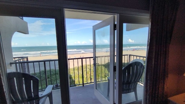 A balcony with a view of the beach and ocean. There are two chairs and a table on the balcony. - Florence I 307 Minium 1 Bedroom Condo by RedAwning (South Padre Island)