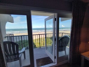 A balcony with a view of the beach and ocean. There are two chairs and a table on the balcony. - Florence I 307 Minium 1 Bedroom Condo by RedAwning (South Padre Island)