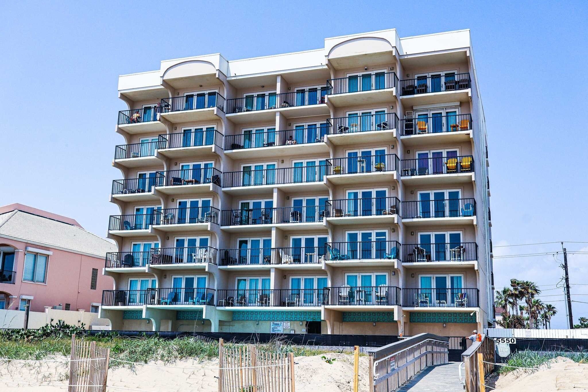 Ein mehrstöckiges Hotel mit Balkonen, Blick auf den Strand und einem Sandparterre.