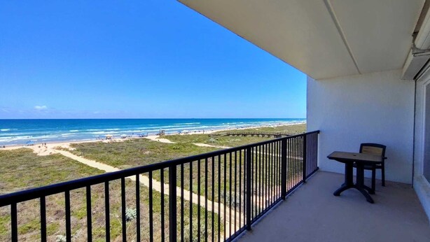 A balcony with a view of the beach and ocean.