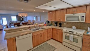 A modern kitchen with wooden cabinets, a dishwasher, a microwave, and a stove. - Edgewater 507 Minium 3 Bedroom Condo by RedAwning (South Padre Island)