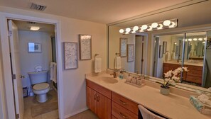Une salle de bain avec un grand miroir, un meuble-lavabo et des toilettes.