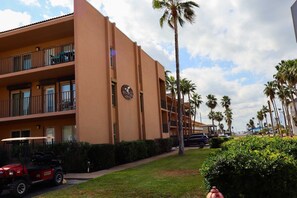 Ein mehrstöckiges Hotel mit Balkonen, Palmen und einem Golfwagen.
