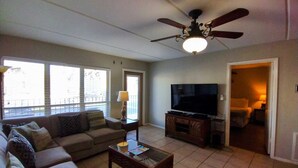 Ein Wohnzimmer mit Sofa, Couchtisch, Fernseher und Deckenventilator.
